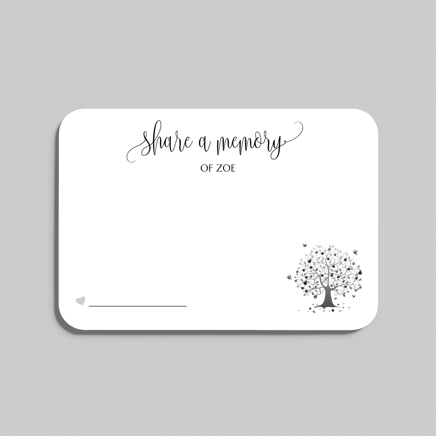 A white rectangular memorial card with rounded corners, featuring the black script text share a memory at the top, a small heart icon with a line at the bottom left, and a black tree illustration with scattered leaves in the lower right. The card is centered on a light gray background.