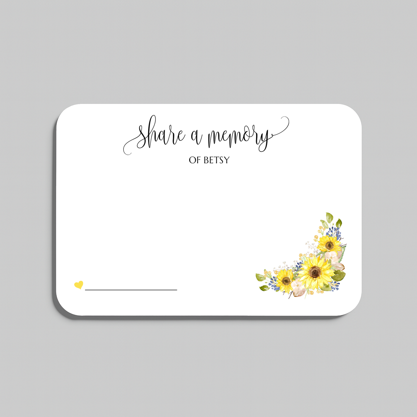 A white rectangular memorial card with rounded corners, featuring the script text 'share a memory' at the top, a blank line at the bottom left for writing a name, and a watercolor sunflower cluster in yellow, green, and blue at the bottom right. The card is shown on a neutral gray background.