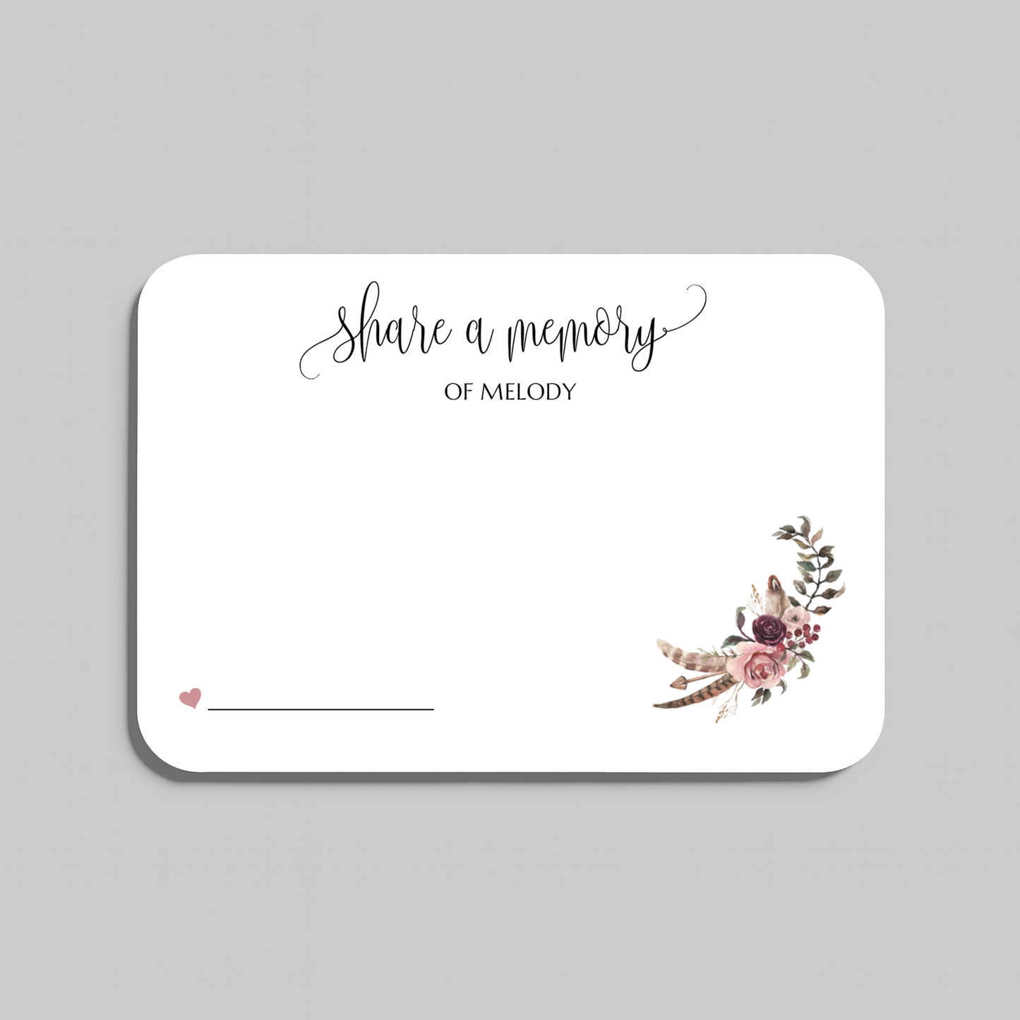 A rectangular white wedding reception card with rounded corners, featuring the script text 'share a memory' at the top, a small pink heart and writing line in the lower left, and a boho floral bouquet illustration in the lower right. The card is shown on a neutral gray background.