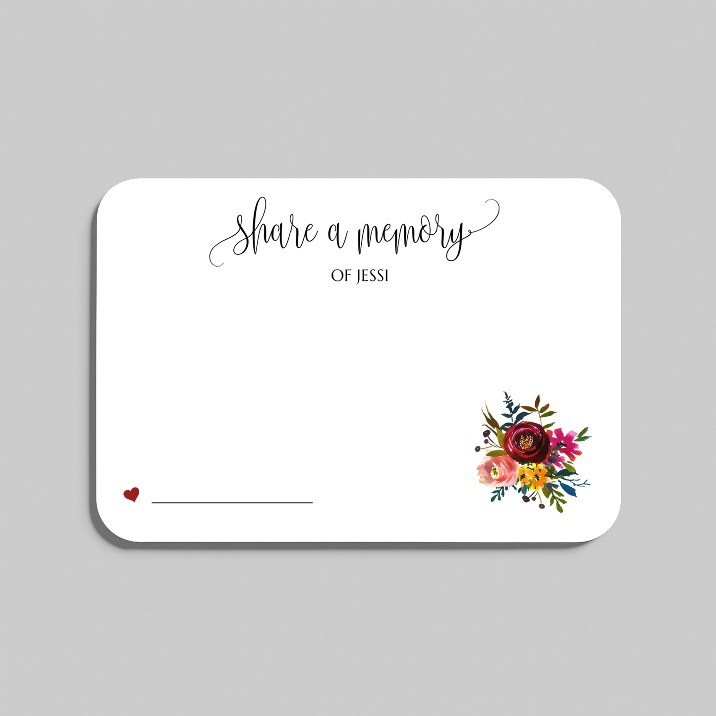 A white rectangular memorial card with rounded corners, printed with the words 'share a memory' in black script and serif text, a small red heart and line on the lower left, and a colorful floral bouquet illustration on the lower right. The card is centered on a light gray background.