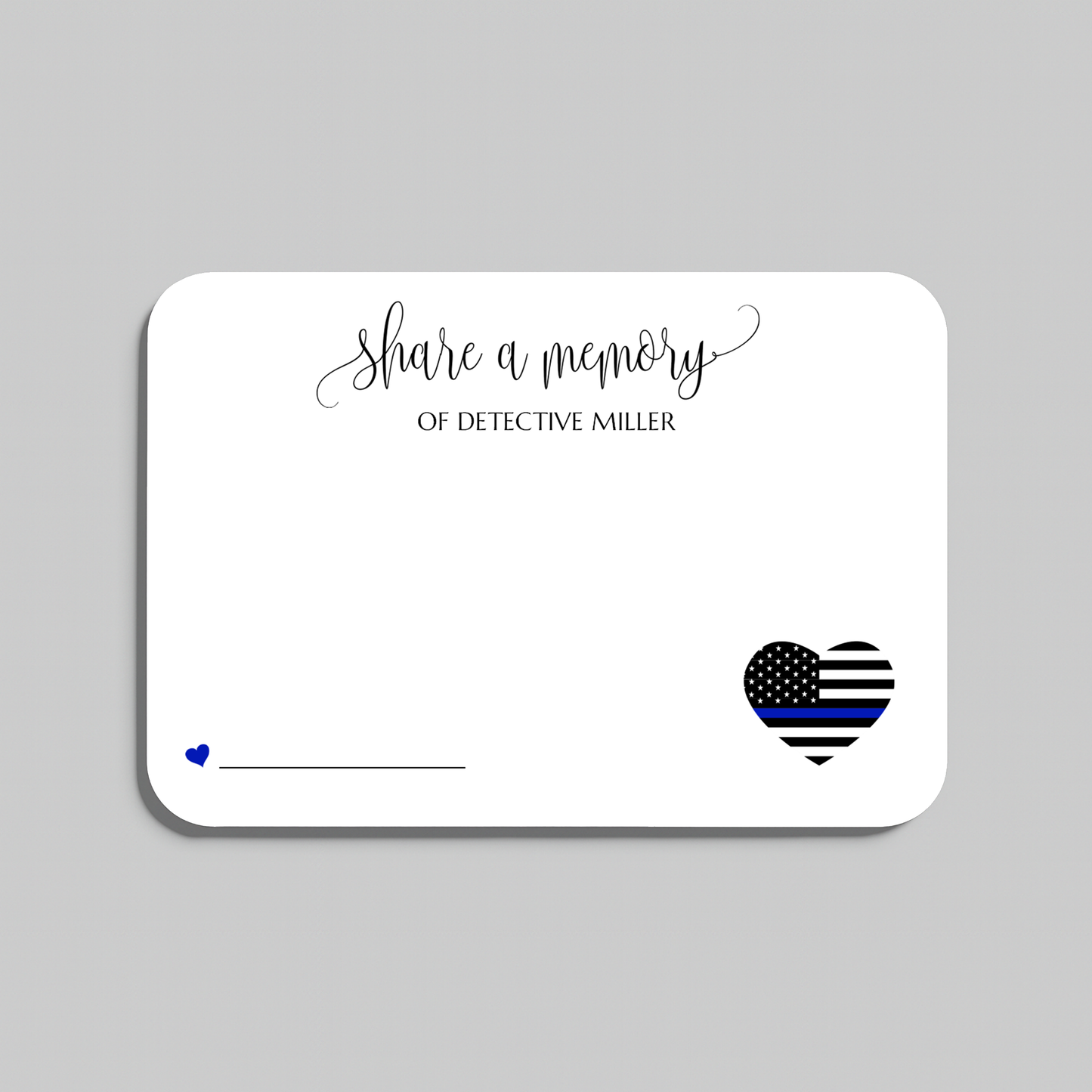 A white rectangular memorial card with rounded corners on a light gray background. The card features the script text 'share a memory' at the top, a small blue heart and line on the lower left, and a black-and-white striped heart with a blue stripe on the lower right for law enforcement memorials