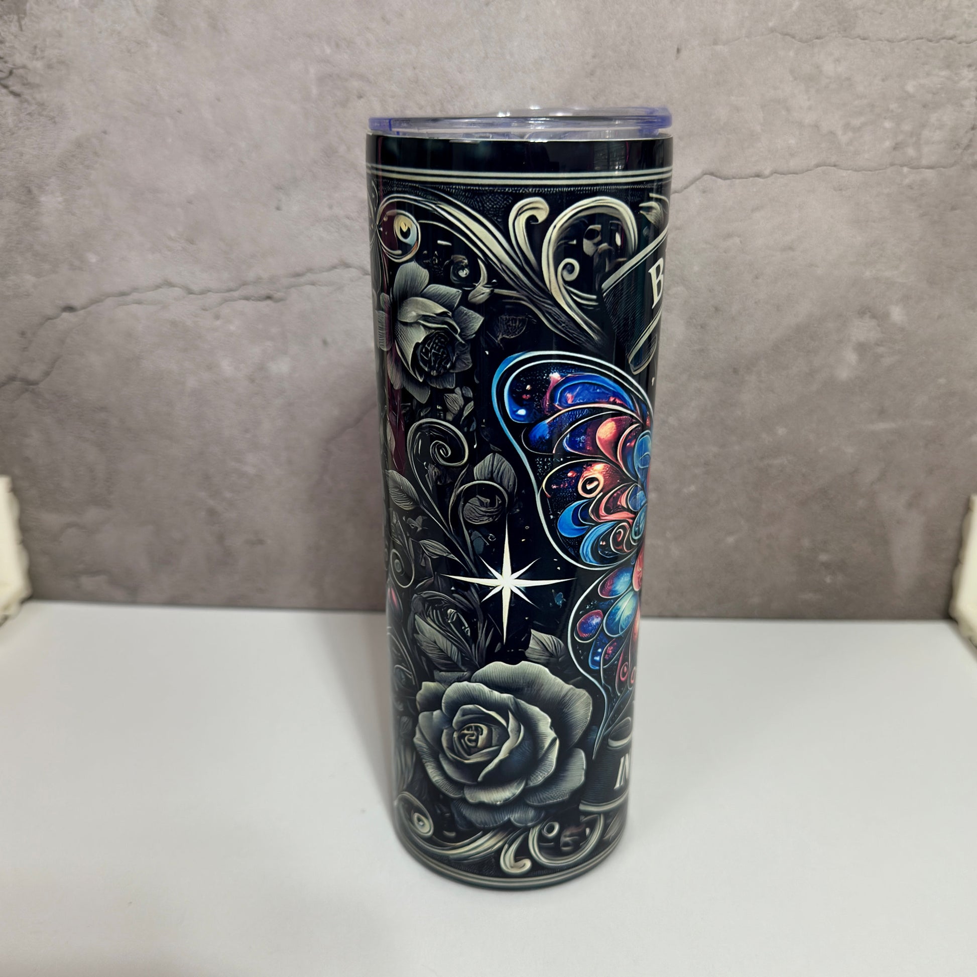 Tumbler with floral and butterfly design on a gray background