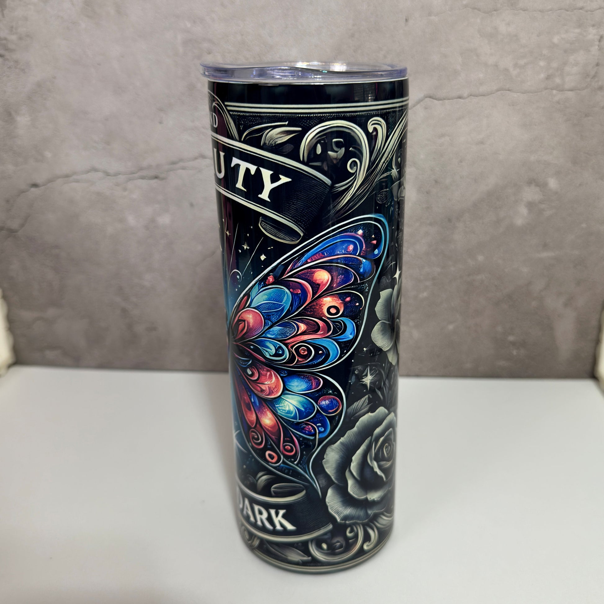 Tumbler with butterfly design and text on a gray background