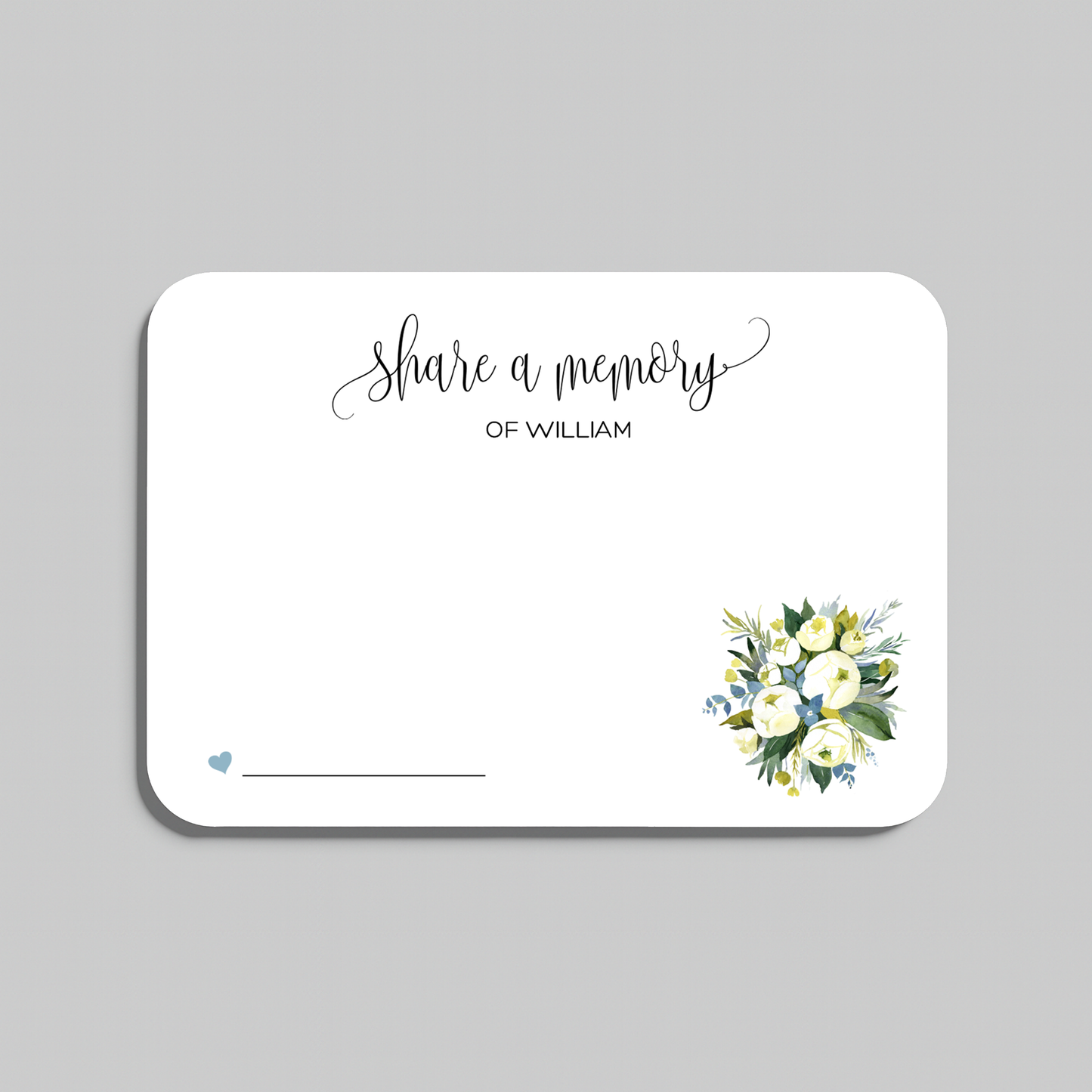 A rectangular white memorial card with rounded corners, featuring the script text 'Share a memory at the top, a small blue heart and line at the bottom left, and a watercolor floral bouquet in white, yellow, and green at the bottom right. The card is shown on a light gray background.