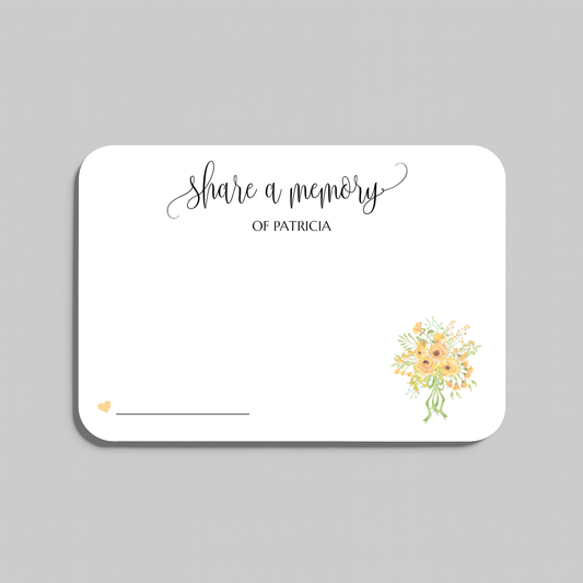 A white rectangular memorial card with rounded corners, printed with the words share a memory in black script and serif text, a small yellow heart near the lower left, a blank line for writing, and a small watercolor bouquet of yellow and peach flowers in the lower right. The card is centered on a light gray background.