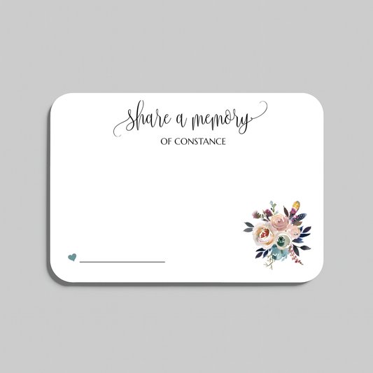 A rectangular white wedding reception seating card with rounded corners, featuring the script text share a memory at the top, a small teal heart and line at the bottom left, and a watercolor floral bouquet illustration at the bottom right. The card is shown on a neutral gray background.