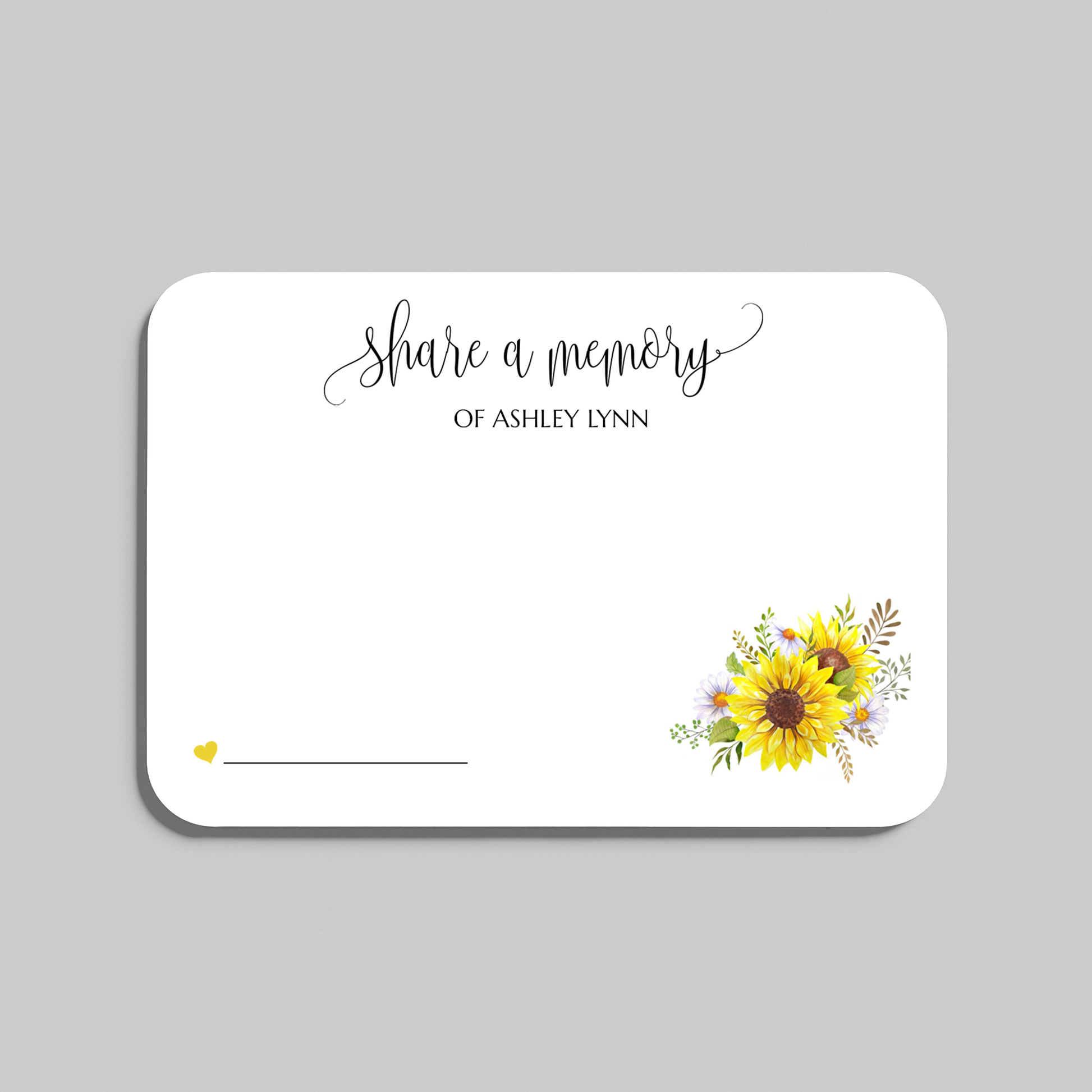 A white memorial keepsake card with rounded corners, featuring the script text 'share a memory' at the top, a small yellow heart and line in the lower left, and a watercolor sunflower and floral arrangement in the lower right. The card is shown on a neutral gray background.