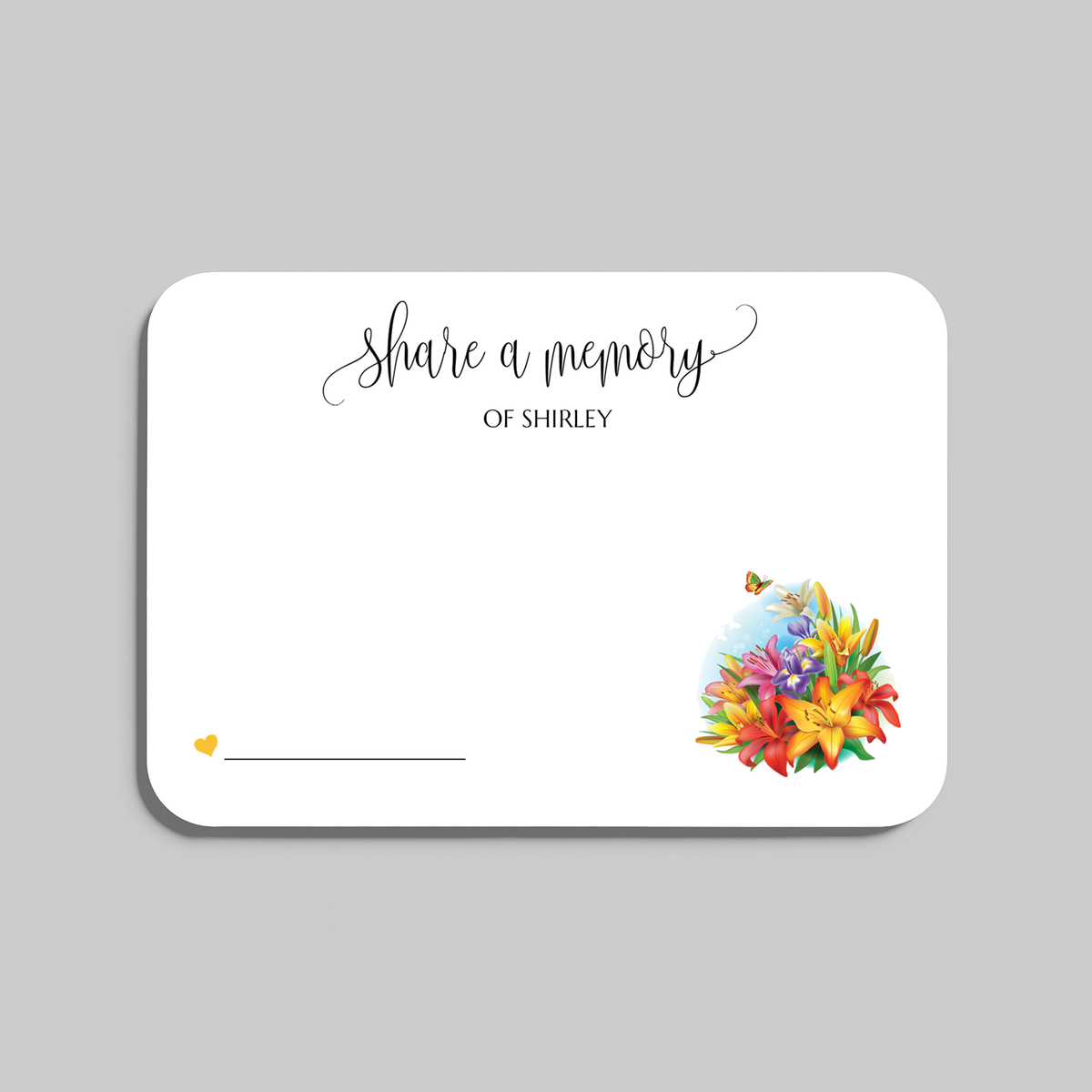 A white rectangular memorial card with rounded corners, printed with the words 'share a memory' in black script and serif text, plus a small yellow heart and a colorful floral illustration in the lower right. The card is shown on a light gray background.