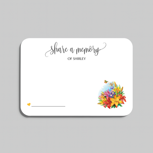 A white rectangular memorial card with rounded corners, printed with the words 'share a memory' in black script and serif text, plus a small yellow heart and a colorful floral illustration in the lower right. The card is shown on a light gray background.