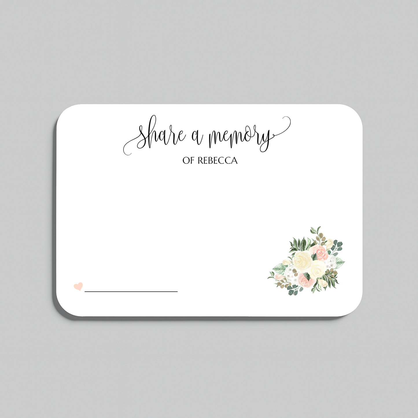A rectangular white memorial card with rounded corners, printed with the words 'share a memory' in black script and serif text, plus a small floral bouquet illustration in soft pink, cream, and green near the lower right. The card is shown on a light gray background.
