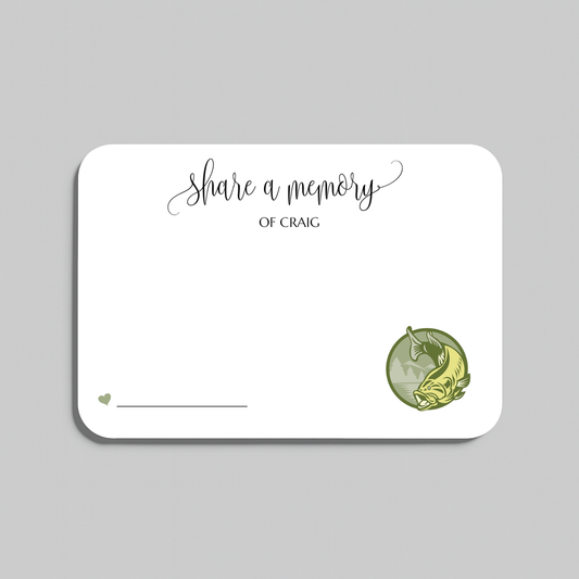 A white rectangular memorial card with rounded corners, featuring the printed text 'share a memory' in black script and serif type, a small heart and line in the lower left, and a green circular illustration of a bass fish in the lower right. The card is centered on a light gray background.