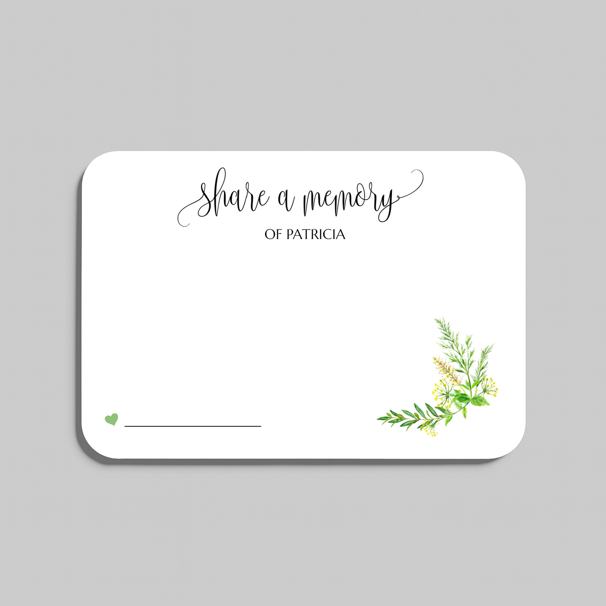 A white rectangular memorial card with rounded corners, featuring the script text 'share a memory' at the top, a small green heart and line at the bottom left, and a delicate green and yellow floral illustration in the lower right corner. The card is centered on a solid gray background.
