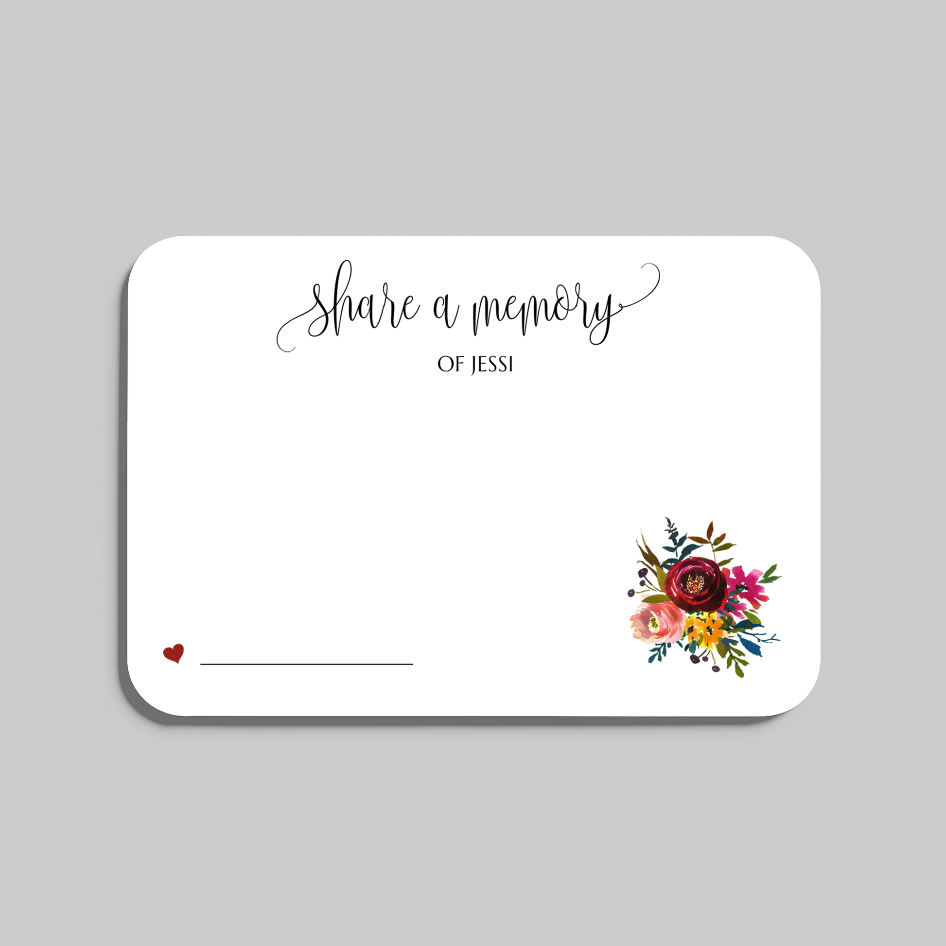 A white rectangular memorial card with rounded corners, printed with the words 'share a memory' in black script and serif text, a small red heart and line on the lower left, and a colorful floral bouquet illustration on the lower right. The card is centered on a light gray background.